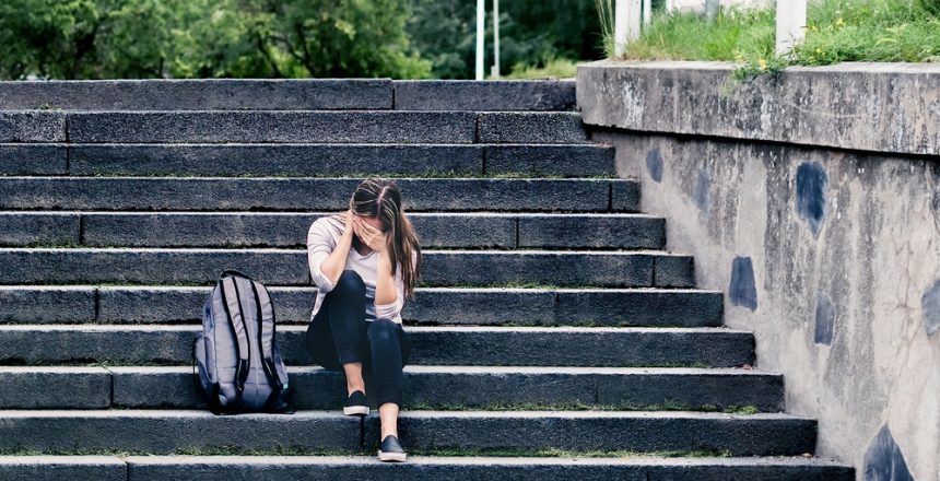 Featured image showing a young woman alone and distraught on the school steps.