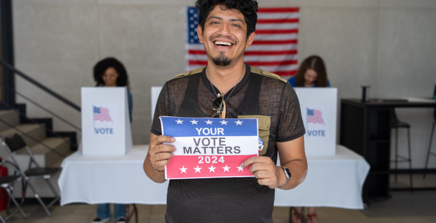Featured image showing a young man at the polls smiling and holding a sign that states "Your Vote Matters".